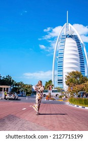 Dubai, UAE. February 14, 2021. Sexy lady is walking in front of the Burj al Arab luxury hotel seen from Medinat Jumeirah, Dubai