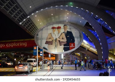 Dubai, UAE - February 19, 2015: Giant Emirates Airlines Hello Tomorrow Billboard And Passengers Outside Dubai International Airport.