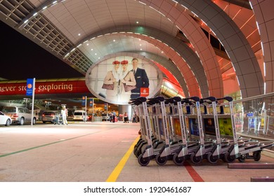 Dubai, UAE - February 19, 2015: Airport Passenger Trolleys And In The Background Emirates Airlines Hello Tomorrow Billboard Outside Dubai International Airport.