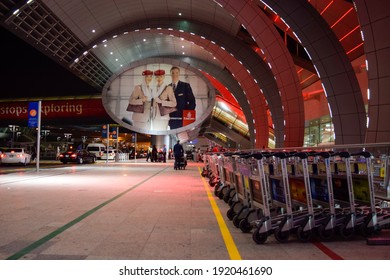 Dubai, UAE - February 19, 2015: Airport Passenger Trolleys And In The Background Emirates Airlines Hello Tomorrow Billboard Outside Dubai International Airport.