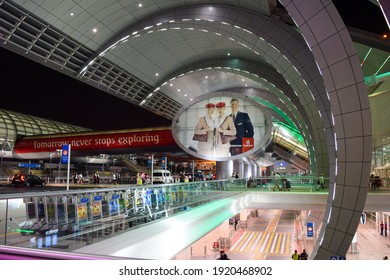 Dubai, UAE - February 19, 2015: Giant Emirates Airlines Hello Tomorrow Billboard And Passengers Outside Dubai International Airport At Night.