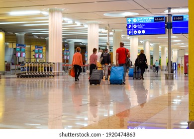 Dubai, UAE - February 19, 2015: Back view of walking passengers with luggage inside Dubai International Airport terminal 3.