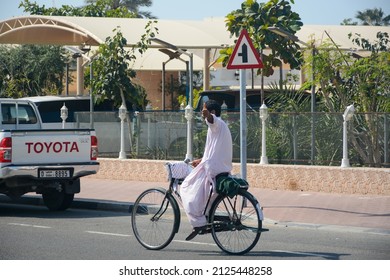 Dubai, UAE - February 3, 2022: Man on the bicycle in Kandura national dress in Al Wasl district