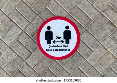 Dubai / UAE - June 10, 2020: "Keep safe distance" sticker sign on a street pavement next to metro station in english and arabic languages. Social distancing in 2 meters during Covid-19, coronavirus.