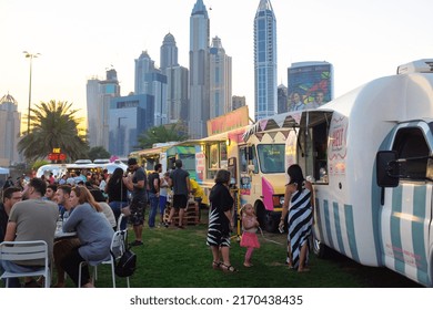 Dubai, UAE - March 26, 2016: People Lounging Near Food Trucks At The Food Truck Jam, A Weekend Event With Food Trucks And Live Music At The Emirates Golf Club. Dubai Media City In The Backdrop.