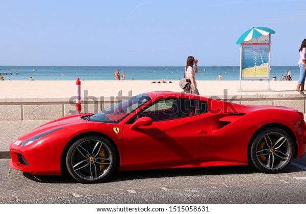DUBAI, UAE - NOVEMBER 23,\
2017: People walk by Ferrari 488 GTB in Dubai, United Arab\
Emirates. Dubai city has a car ownership rate of 541 cars per 1,000\
population.