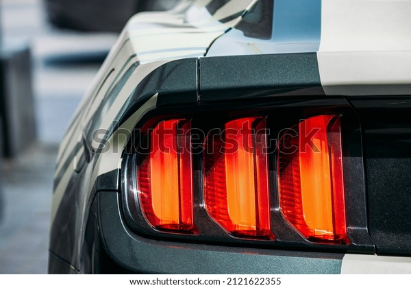 Dubai, UAE, United Arab Emirates - May 25, 2021:\
Close Up Headlight Of Black Color Ford Mustang Car Parked At\
Street. Back View. Ford Mustang is series of American automobiles\
manufactured by Ford