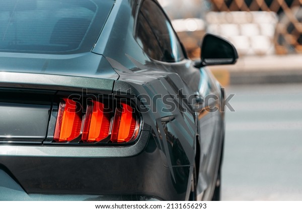 Dubai, UAE, United Arab Emirates - May 25, 2021:\
Headlight Of Black Color Ford Mustang Car Parked At Street. Back\
View. Ford Mustang is series of American automobiles manufactured\
by Ford. High