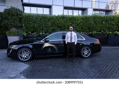 Dubai, UAEmirates - Dec 12 2021: Emirates First Class taxi driver waits next to his black Mercedes S 450 for an Emirates first class customer for an airport transfer.

