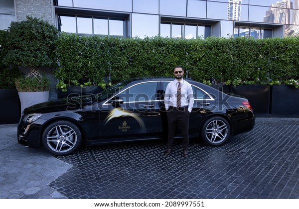 Dubai, UAEmirates -\
Dec 12 2021: Emirates First Class taxi driver waits next to his\
black Mercedes S 450 for an Emirates first class customer for an\
airport transfer.\
