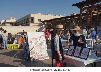 Dubai, United Arab Emirates - 24 October 2015: Woman Visits Table With Framed Artworks At A Hip Art Fair In Al Fahidi. Female Artist Points And Talks About Her Work. Sunny Outdoor Weekend Event.