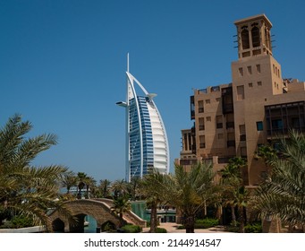 Dubai, United Arab Emirates – 4 6 2022: The Burj Al Arab’s Modern Design Contrasts With The Traditional Arabic Style Of Souk Madinat In Jumeirah, Dubai, With Its Palm-lined Walkways And Waterways.