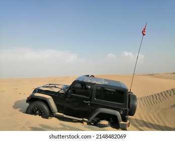 Dubai, United Arab Emirates - April 22, 2022: Jeep Wrangler 4x4 Vehicle (four-wheel-drive, 4WD, SUV) Bogged Down Off-road In Deep Desert Sand Dunes Terrain And Needing Recovery By Another 4x4.