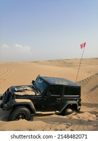 Dubai, United Arab Emirates - April 22, 2022: Jeep Wrangler 4x4 Vehicle (four-wheel-drive, 4WD, SUV) Bogged Down Off-road In Deep Desert Sand Dunes Terrain And Needing Recovery By Another 4x4.