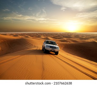 Dubai, United Arab Emirates - December 2004: Car Driving In The Desert, Sunset In The Background.