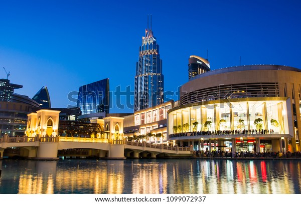 DUBAI,\
UNITED ARAB EMIRATES - FEBRUARY 5, 2018: Dubai mall modern\
architecture reflected in the fountain at blue hour. The Dubai Mall\
is the largest mall in the world by total\
area