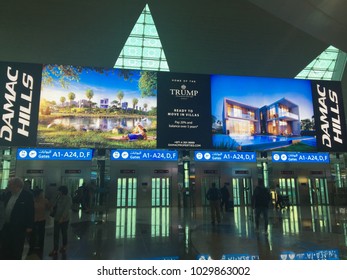 Dubai / United Arab Emirates - May 8 2017: A Large Billboard In Dubai International International Airport Advertising Villas Owned By The Trump Brand With Passengers Walking Around.