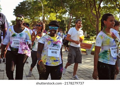 Dubai, United Arab Emirates - November 29, 2013: Black Woman Covered In Colored Powder Looks At The Camera With A Huge Smile As She Walks With A Crowd Through Zabeel Park At A Color Walk.