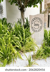 Dubai, United Arab Emirates - October 2021: Summersalt Beach Club Sign Surrounded My Green Plants Growing From White Stones