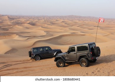 Dubai, United Arab Emirates - September 4, 2020: Jeep Wrangler 4x4s/SUVs/4WDs driving off-road in arid desert sand dunes terrain. Dune bashing is a popular adventure activity in the Arab country.