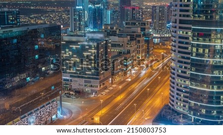 Dubai's business bay office buildings aerial night timelapse with street traffic. Rooftop view of some skyscrapers and new towers under construction