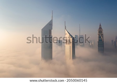 Dubai's futuristic buildings under a blanket of fog in the early morning.