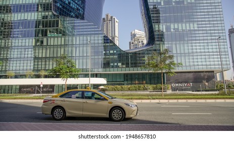 Dubai,UAE - April 02, 2021: The official RTA and cheaper state taxi of Dubai with all the easily recognizable colored car red roof passing infront of Omniyat building in Business Bay