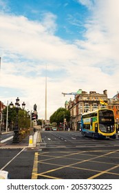 Dublin City, Ireland - 02.10.2021: Traffic Over O'Connell Bridge, Double Decker Bus, Famous Town Landmark Needle In The Background. Blue Cloudy Sky