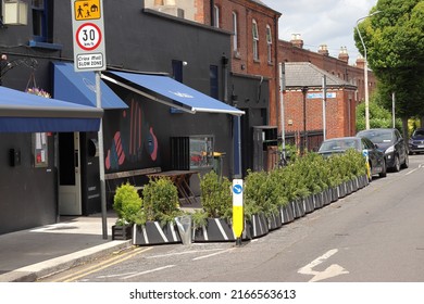 Dublin, Ireland - 06 11 2022: Outdoor dining parklet trial outside Dublin cafe with green plants separating it from the road 