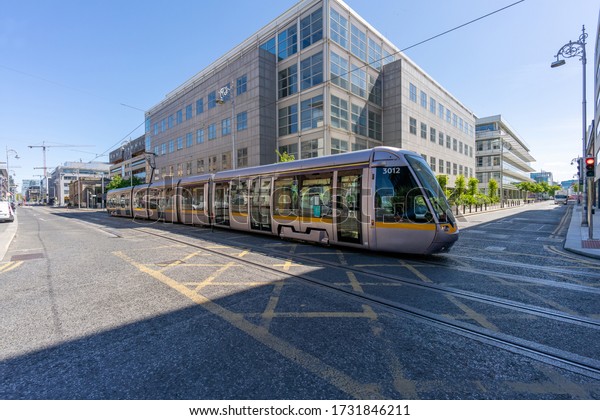 Dublin, Ireland - 14 May 2020: Empty street and LUAS\
tram during coronavirus outbreak in Dublin. George\'s Dock, IFSC\
area