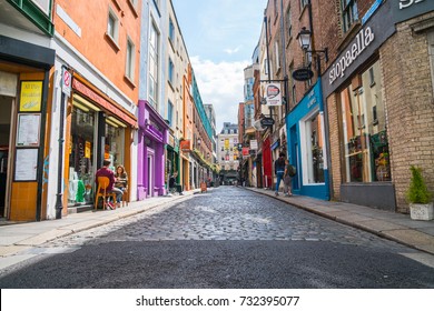 DUBLIN, IRELAND - AUGUST 10;  Few People Seated Outside Cafe And Walking In Shop  Lined Narrow Quaint Cobbled Street In Temple Bar Area With Shop Signage On Both Sides August 10, 2017 Dublin Ireland