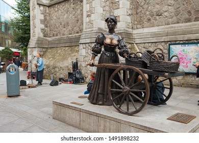 Dublin, Ireland - August 2019: The Bronze Statue Of A Fictional Fishmonger Named Molly Malone, With A Busker Performing In The Background