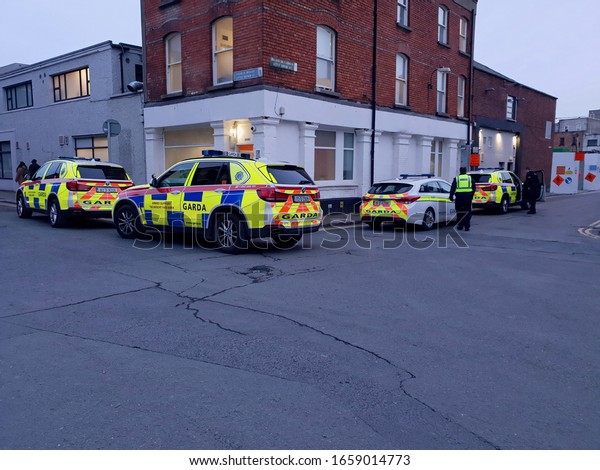 DUBLIN, IRELAND - FEBRUARY 26, 2020: Irish\
Gardai officers on duty at the evening time. Garda vehicles parked\
on the crossroads in Dublin city\
center.