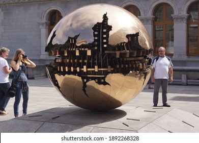 Dublin, Ireland - July 12 2014: people photographing Sphere Within Sphere (sfera con sfera) by Italian artist Arnaldo Pomodoro at the Berkeley Library, Trinity College