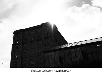 DUBLIN, IRELAND - May 19, 2022: A Grayscale Of The Sun Shining Behind An Old Stone Building In Dublin, Ireland