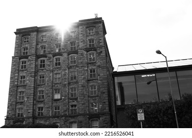 DUBLIN, IRELAND - May 19, 2022: A Grayscale Of The Sun Shining Behind An Old Stone Building In Dublin, Ireland