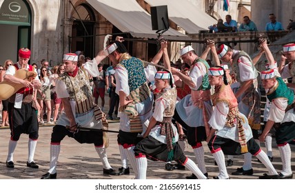 Dubrovnik, Croatia - 11 May 2022 : Old town square, national croatian dance show, young men in folk costumes dancing, entrance of Church Sveti Vlaho or St. Blaise