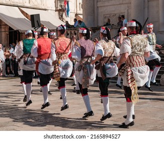 Dubrovnik, Croatia - 11 May 2022: Old town square, national croatian dance show, young men in folk costumes dancing,  entrance of Church Sveti Vlaho or St. Blaise