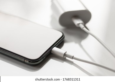 Dubrovnik, Croatia - July 2, 2020: Apple smartphone charger charging iPhone isolated on white background