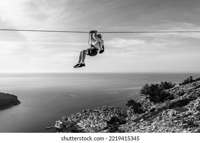 Dubrovnik, Croatia - October 2022: Unidentifiable Man Ziplining Above Dubrovnik Old Town; Thrill Seeking Holiday Adventure; Extreme Sport; Panoramic View Of The Old Town And Adriatic Sea