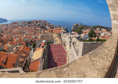 Dubrovnik, Croatia, old town panorama from the height of medieval fortress walls, with rooftops and Fort Lovrijenac in  background. Fun basketball court located on the roofs and adapted to space. - Powered by Shutterstock