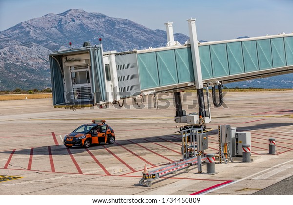 DUBROVNIK, CROATIA - SEPTEMBER 1 2017: The\
ground crew of Dubrovnik airport is waiting for the plane to\
arrive, parked in the shade of the air bridge\
jetway.