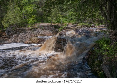 Duchesnay Falls And Cascades North Bay Ontario Canada In Summer, Sunny Day, Root Beer Color Water, Green Forest, Sunny And High Contrast