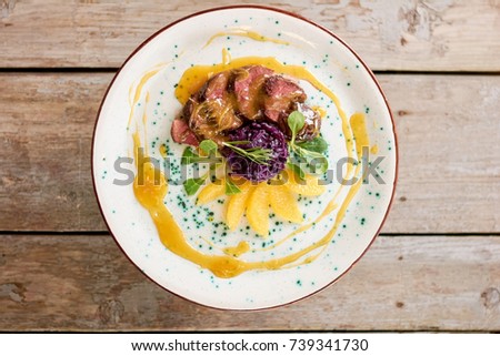 Duck breast with orange sauce, top view. Slices of roasted duck meat with orange sauce and salad. Tasty and beautiful dinner at restaurant.