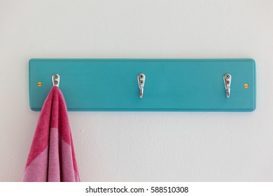 A duck egg coloured coat or towel hook with a pink towel hanging from it