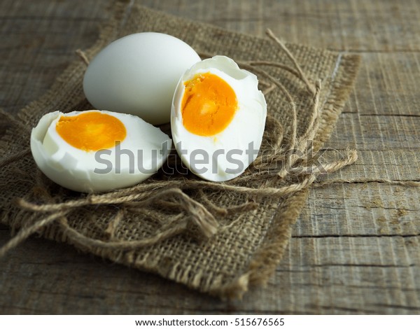 Duck eggs, white eggs, salted eggs\
with yolk on old sack and ropes with wooden\
background.