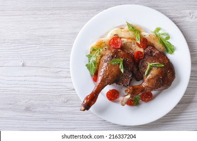 duck legs baked with apples and tomatoes on white plate close-up view from above. horizontal  