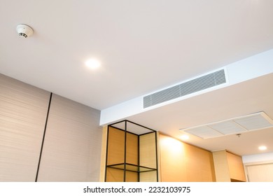Duct air conditioner for home or office. Ceiling mounted cassette type air conditioner and modern lamp light on white ceiling.