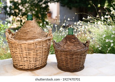 Due Demijohn In A Garden, Made In Puglia Are A Glass Container, Covered With A Wicker Weave In The Shape Of A Basket And With A Wooden Bottom, Capable Of Containing, Traditional Way To Preserve Wine