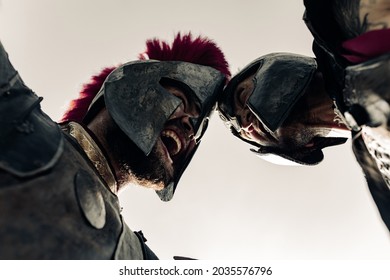 Duel between two screaming in rage ancient greek warriors in battle dress against sky background.
